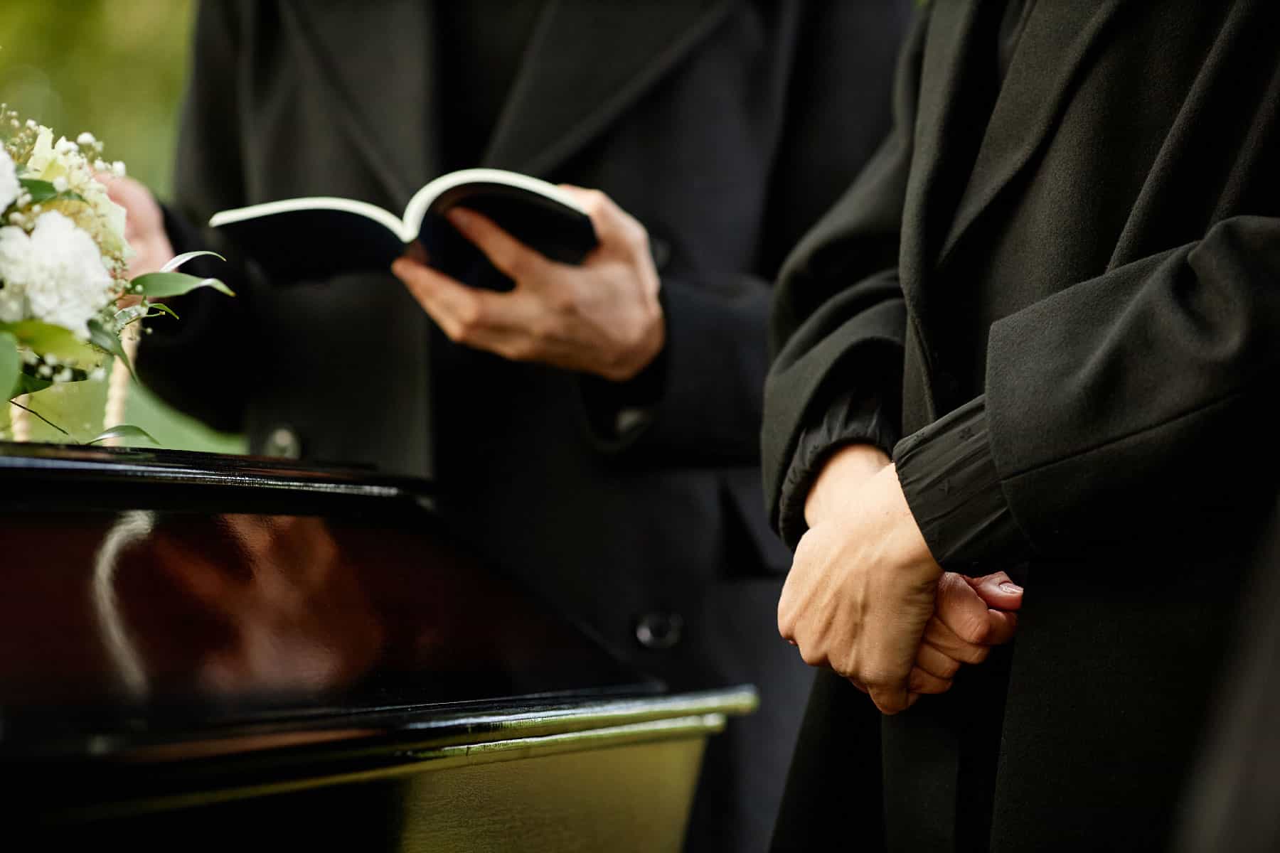 Close up young woman standing by coffin at a funeral